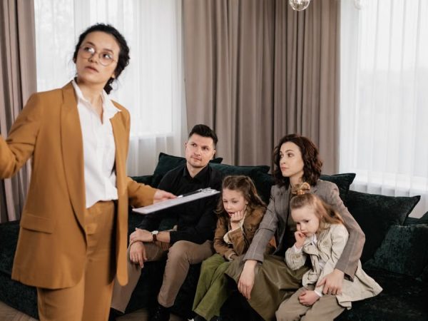 A real estate agent presenting property options to a family in a living room setting.